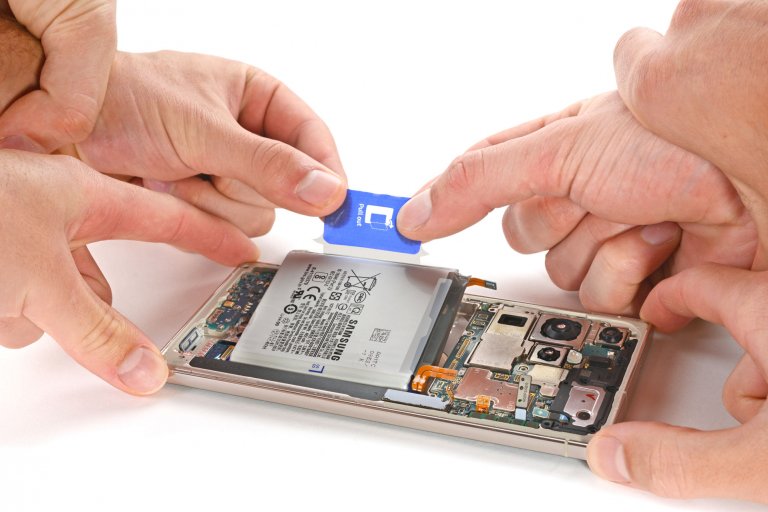 Three sets of hands pulling on a Samsung Galaxy S23 Ultra's battery tab.