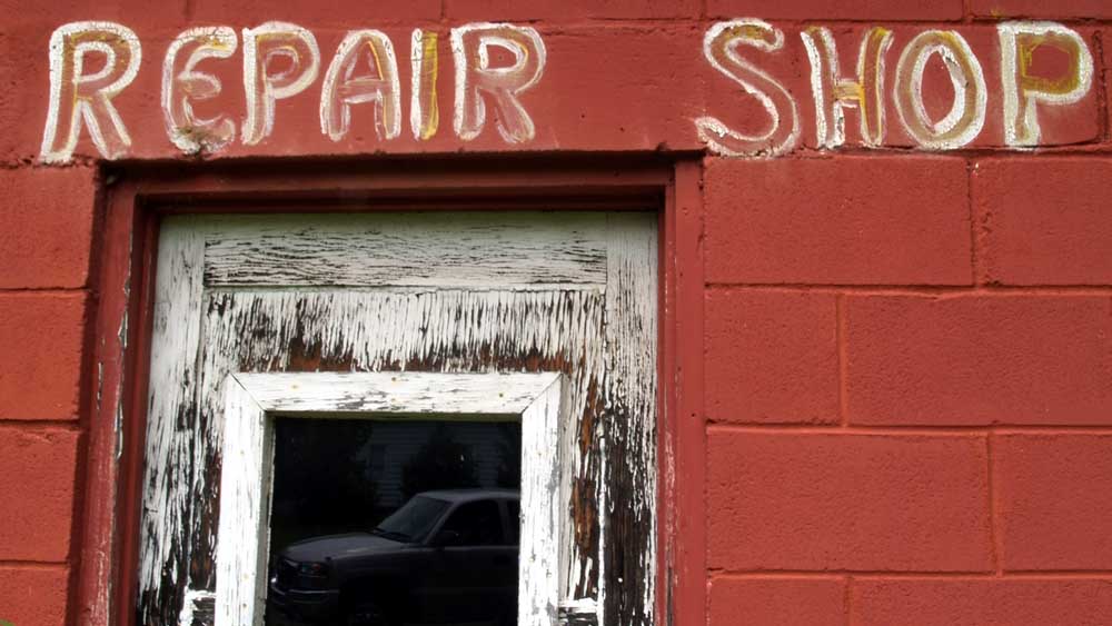 Hand-painted letters read "repair shop" over a decaying wood door